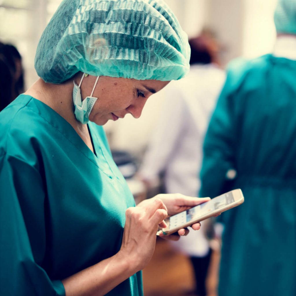 Médecin avec une charlotte surfant sur mon smartphone
